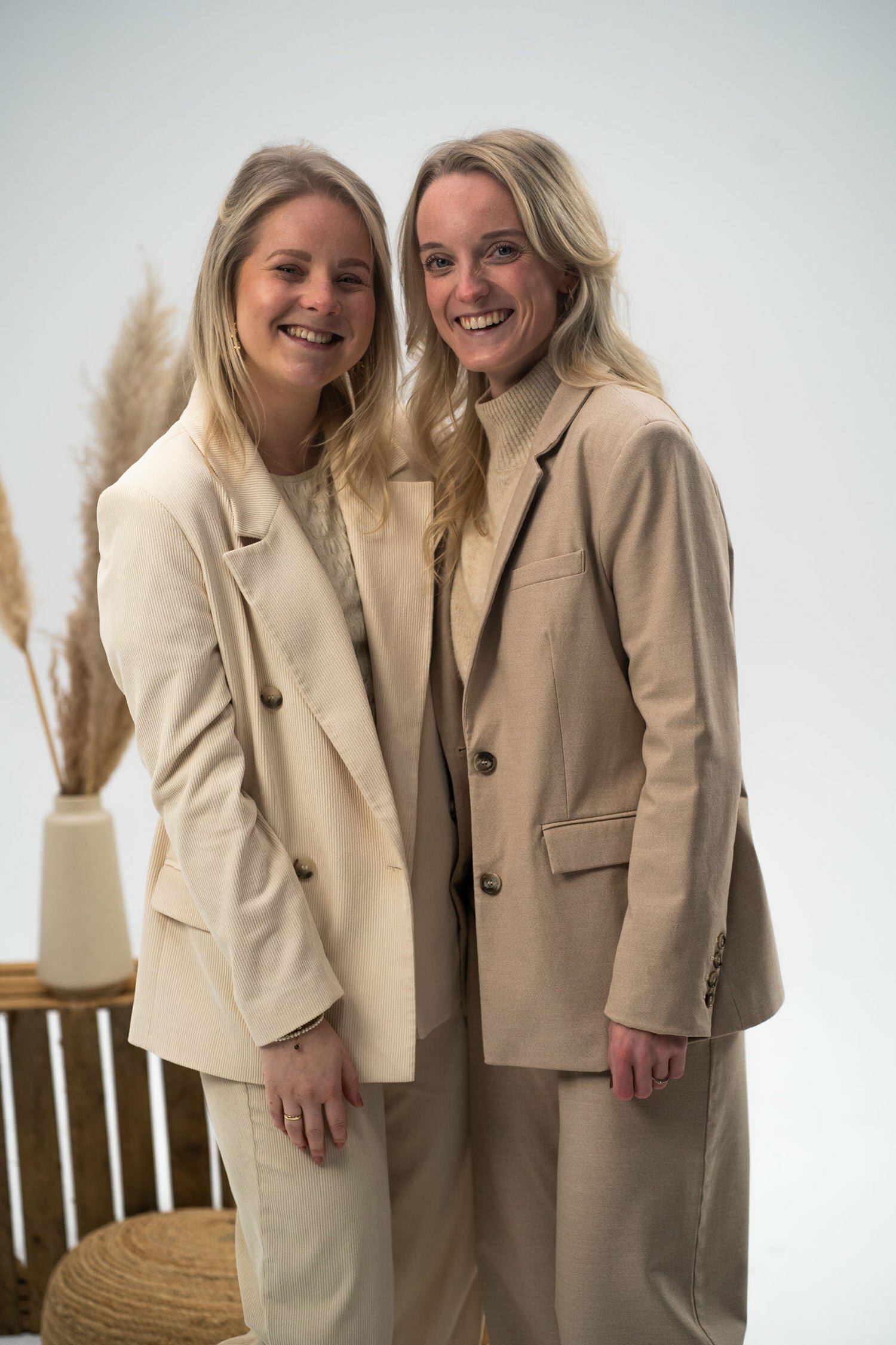 Twee vrouwen in beige pak staand en lachend